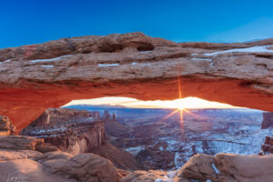 The sun bursts forth and illuminates the underside of Mesa Arch, within Canyonlands National Park.